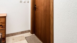 Una puerta de madera con un pequeño ventanal encima, un interruptor de luz y un enchufe en la pared.