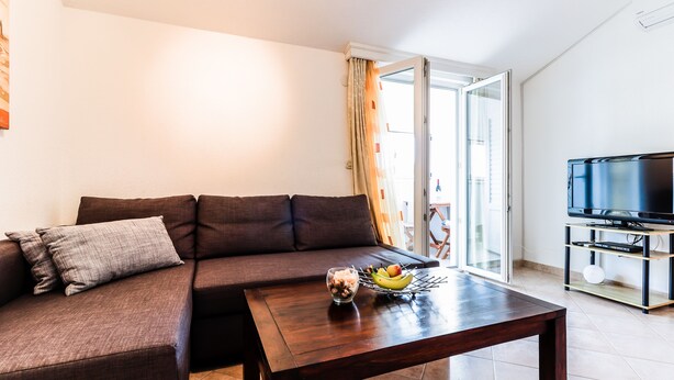 Una sala de estar moderna con un sofá seccional marrón, una mesa de centro de madera y un televisor de pantalla plana sobre un mueble.