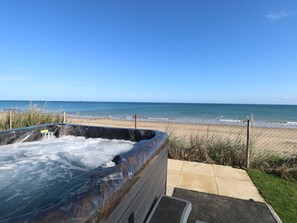 A hot tub with a view of the beach and ocean.