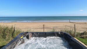 A hot tub with a view of a beach and ocean.