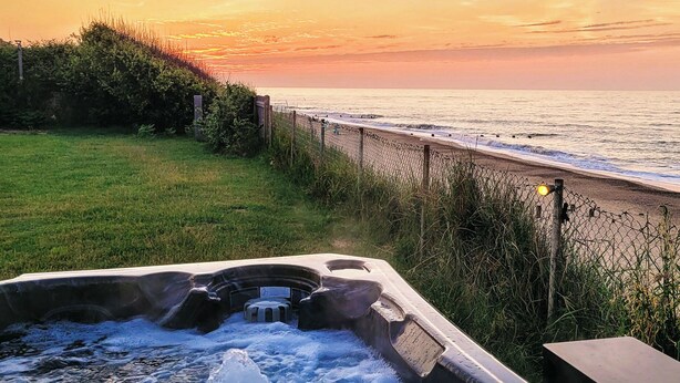 A hot tub with a view of the ocean at sunset.