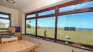 A kitchen with a large window, a wooden table, and a washing machine.