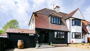 A two-story house with a black exterior, a tiled roof, and a brick chimney.