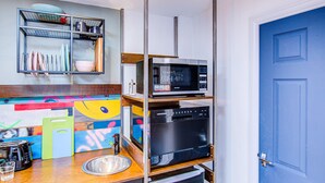 A compact kitchen with a microwave, oven, and dish rack.