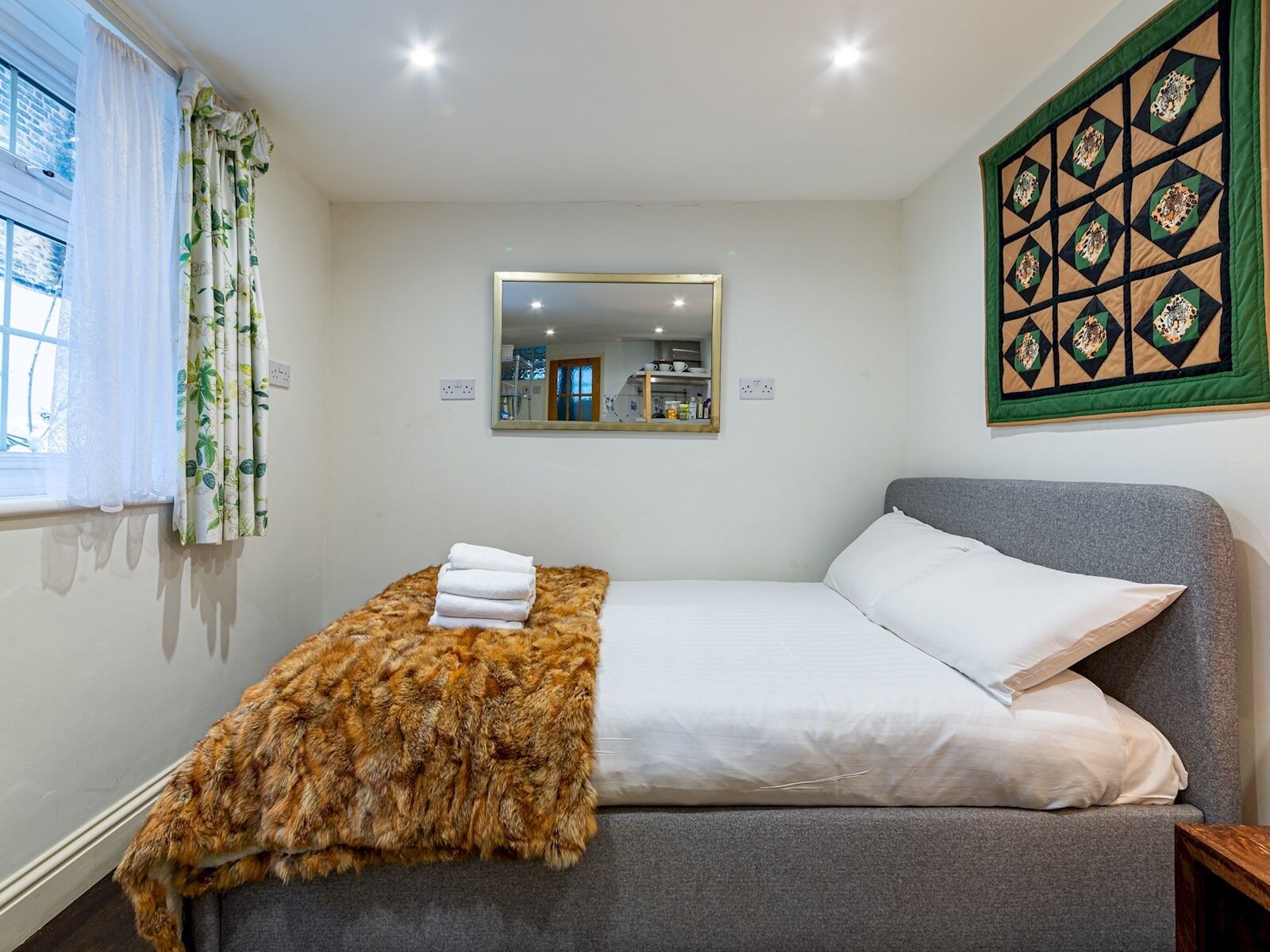 Una camera da letto con un letto, uno specchio e un pannello decorativo a parete.
