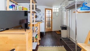 A compact living space with a kitchenette, a television, and a laundry area. - Cozy Brixton Hideaway – Cute & Convenient Stay - Pass the Keys (London)