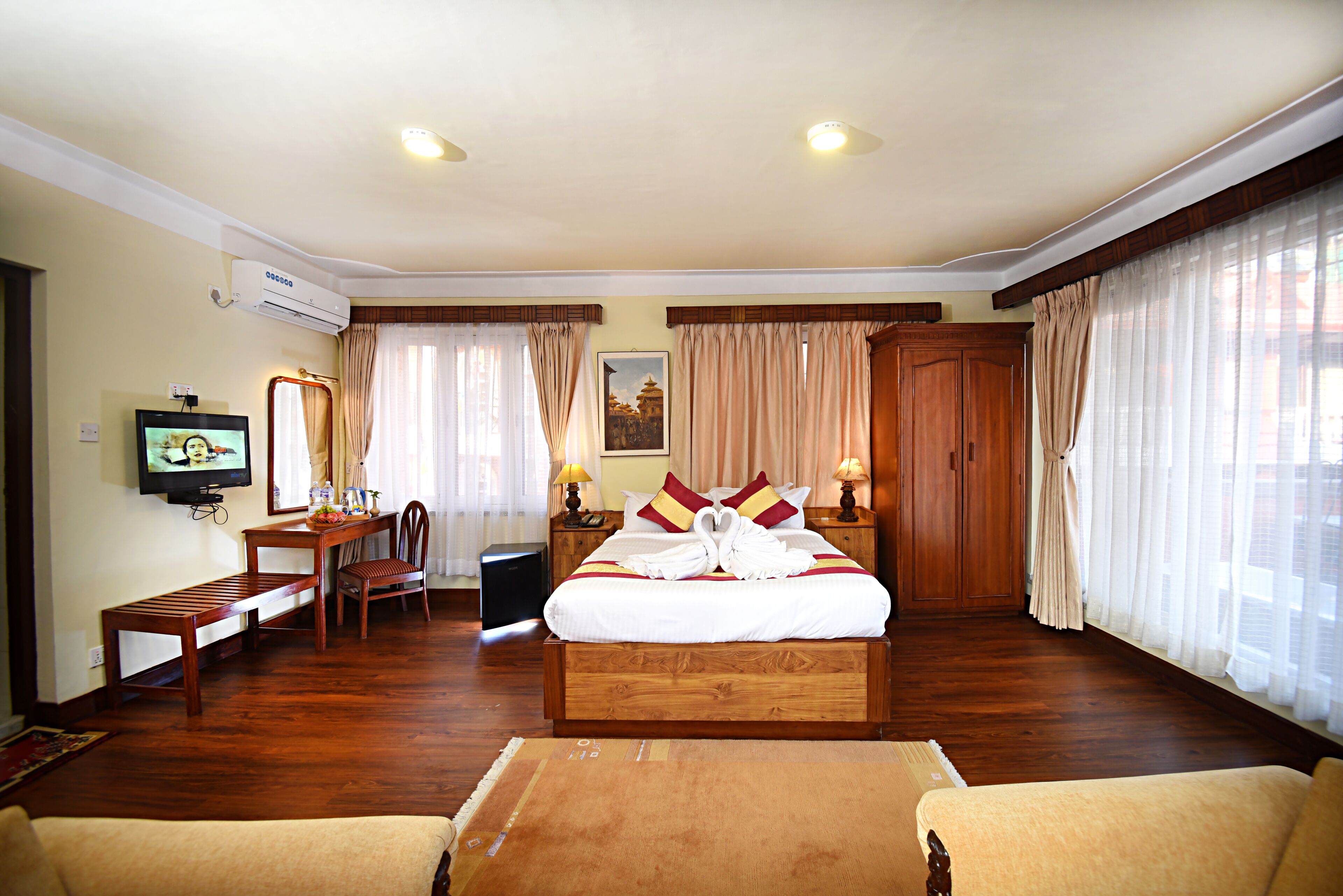 Una habitación de hotel con una cama de madera, televisión, escritorio y silla.