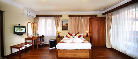 Una camera d'albergo con un letto in legno, una televisione, una scrivania e una sedia.