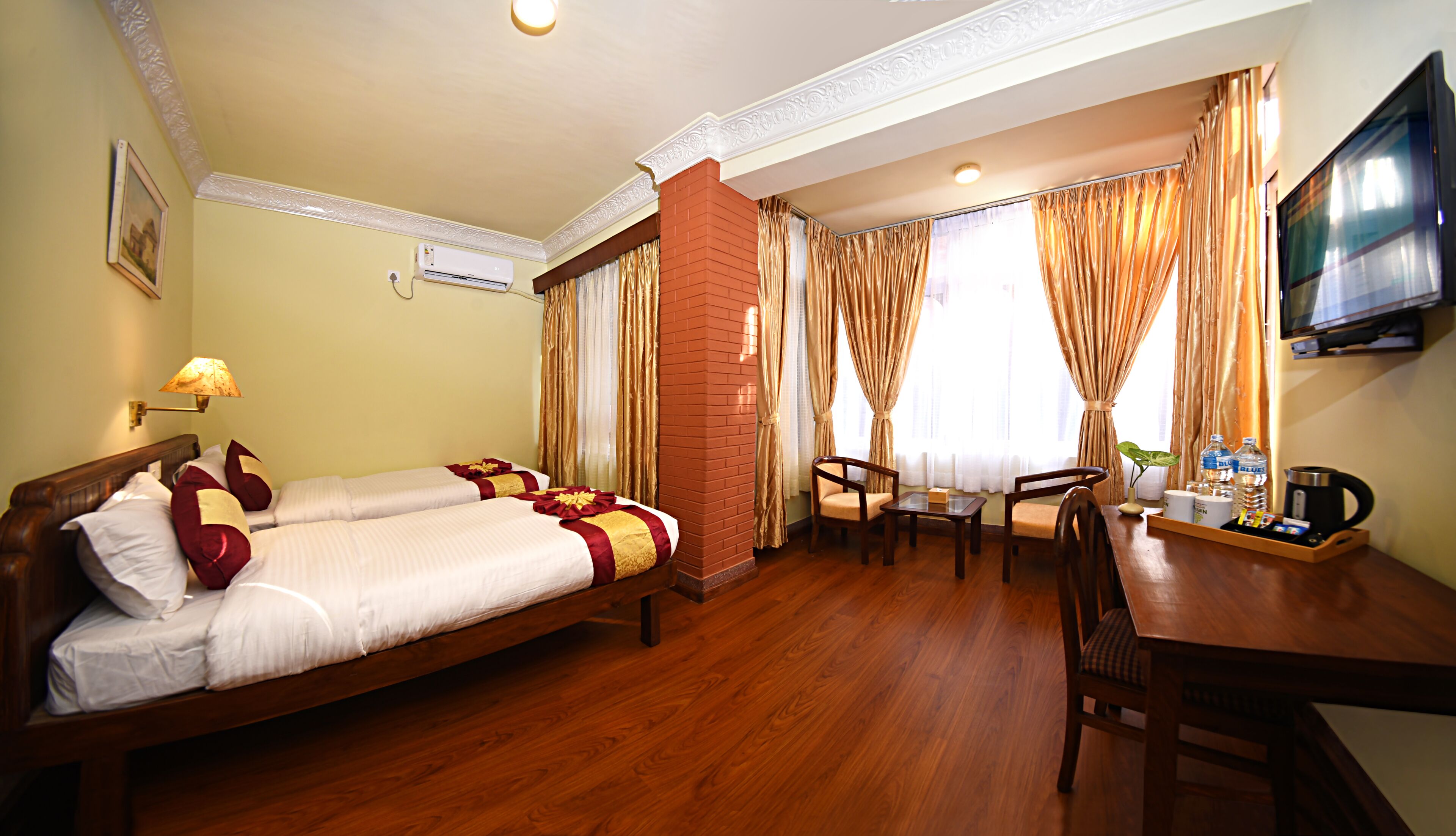 A hotel room with a bed, a desk, a chair, a television, and a window with curtains.