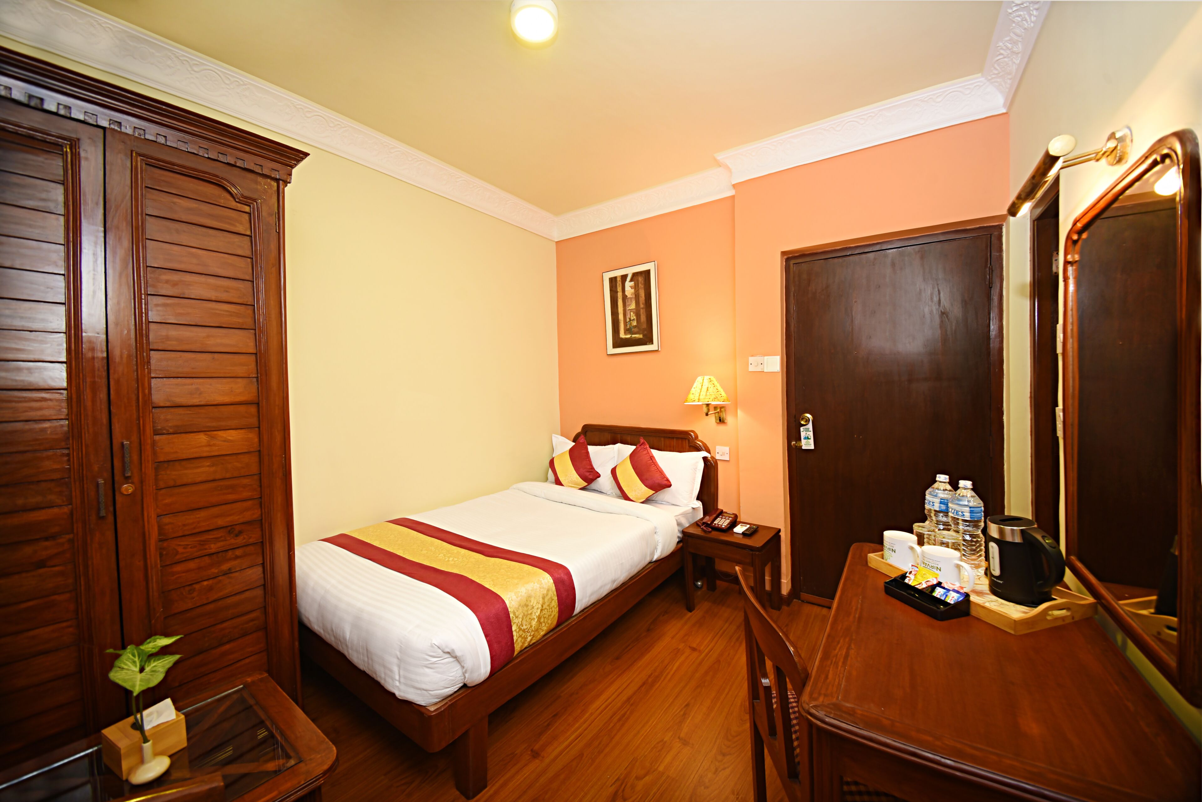 Une chambre d’hôtel avec un lit en bois, une table de chevet et un bureau avec un miroir.