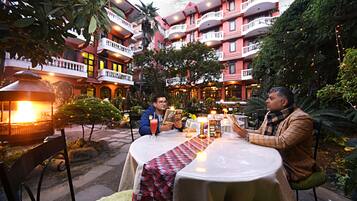 A courtyard with a round table, chairs, and a decorative table runner.