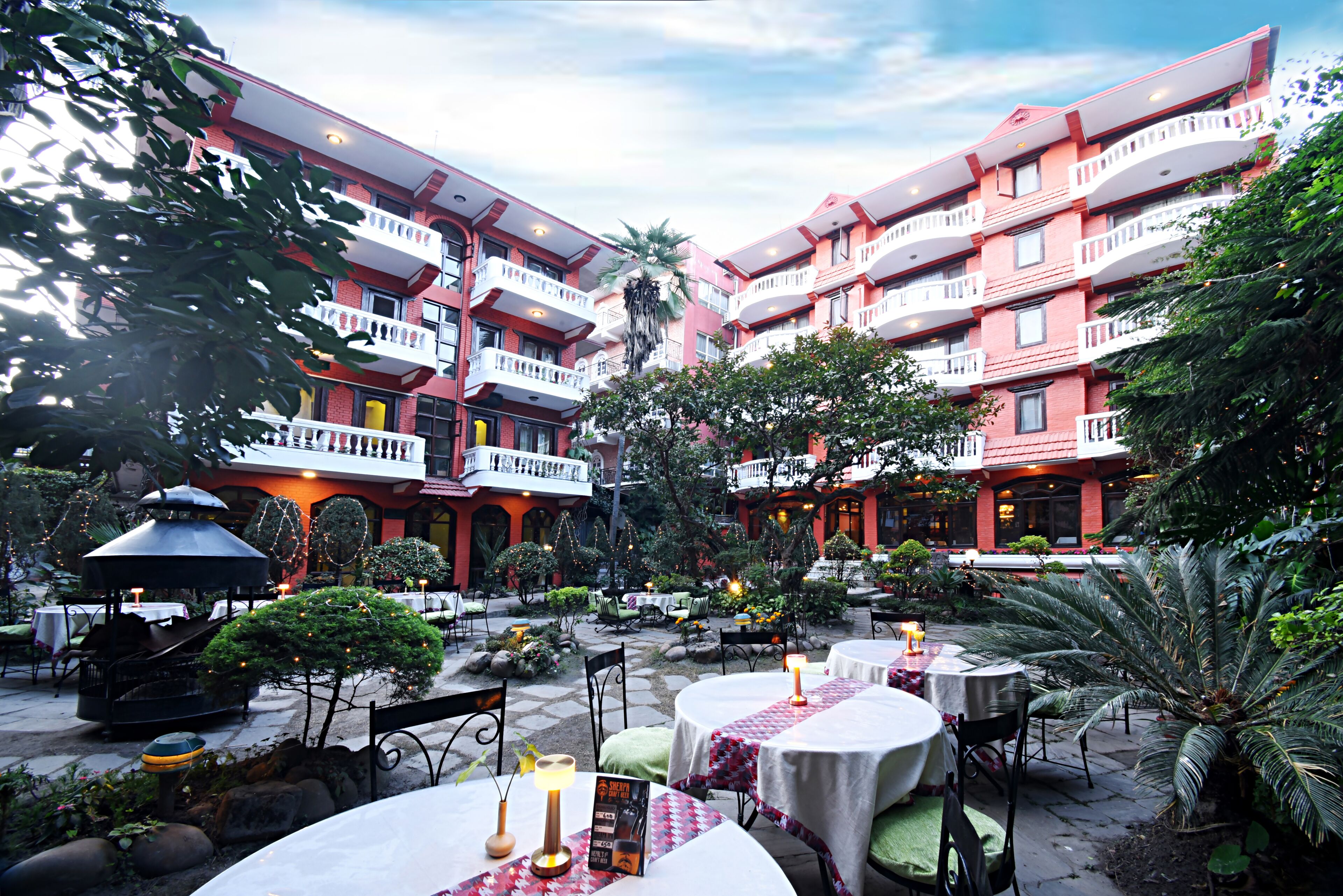 A courtyard with outdoor seating, a gazebo, and a building with multiple balconies.