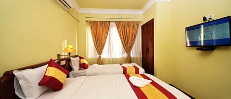 Habitación de hotel con dos camas, televisión, aire acondicionado y cortinas.
