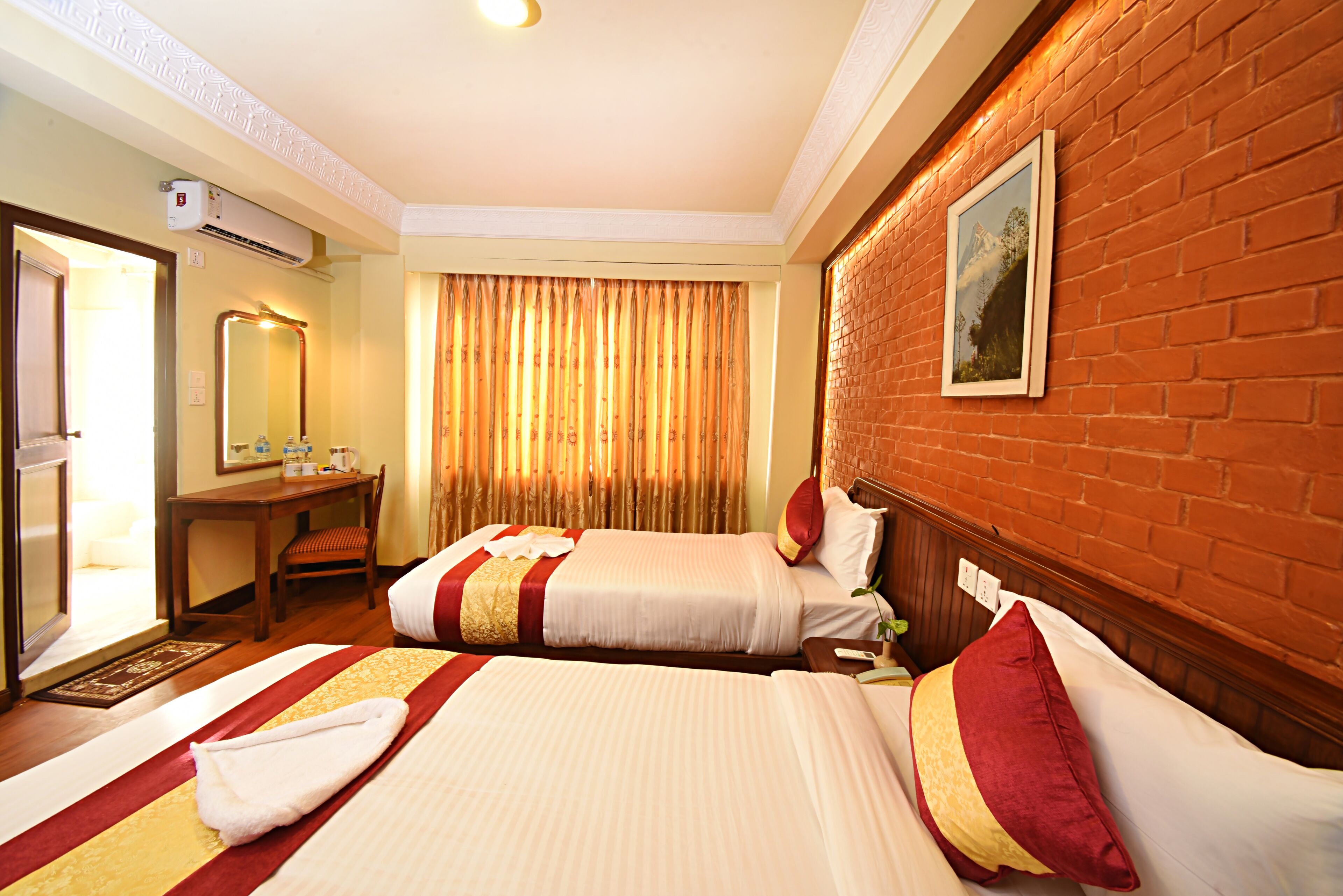 A hotel room with two beds, a desk, a chair, a mirror, and a window with curtains.