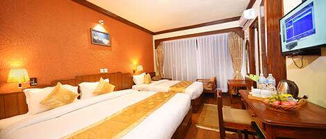 A hotel room with two beds, a desk with a computer, a television, and a window with curtains.