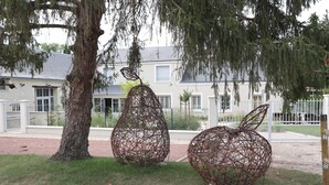 Two spherical sculptures made of intertwined metal wires, located in a grassy area with a tree and a building in the background. - Gite La Loire 4/5 Personnes à la Campagne Prés des Vergers (Lignières-de-Touraine)
