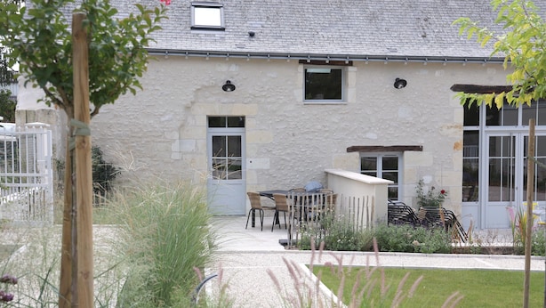 A stone building with a door, windows, and a small outdoor seating area with chairs and a table. - Gite La Loire 4/5 Personnes à la Campagne Prés des Vergers (Lignières-de-Touraine)