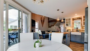Moderni keittiö, jossa on ruokailutila, suuret ikkunat ja portaikko, joka johtaa ylemmälle tasolle.