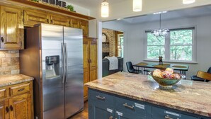 Une cuisine moderne avec des meubles en bois, un réfrigérateur en acier inoxydable et un plan de travail en granit.