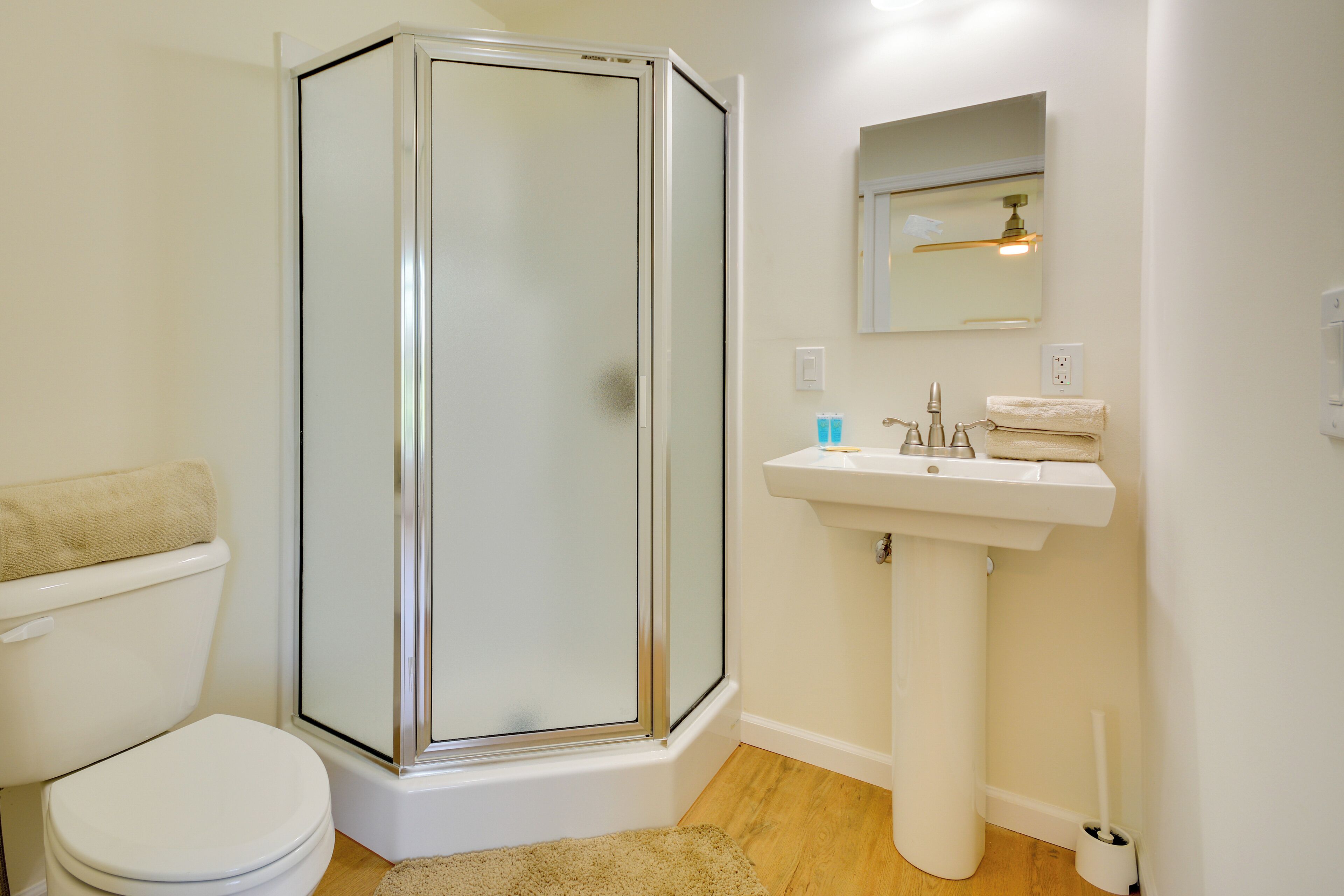 A bathroom with a glass-enclosed shower, a white sink, and a toilet.