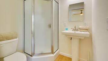 A bathroom with a glass-enclosed shower, a white sink, and a toilet.