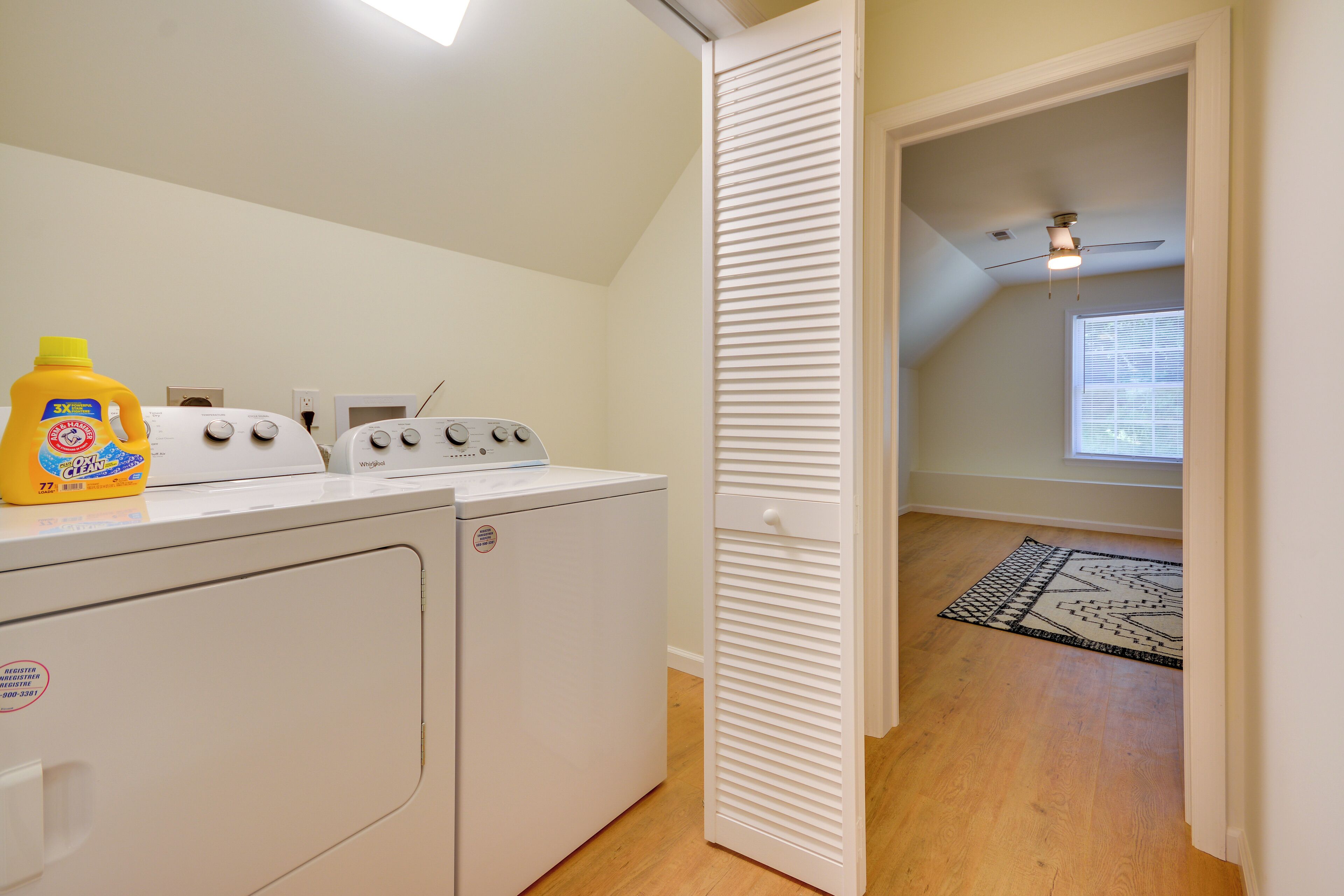 A laundry room with a washing machine, dryer, and a bottle of detergent.