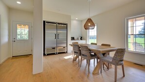 Cozinha moderna com uma ilha grande, eletrodomésticos de aço inoxidável e cadeiras de vime.