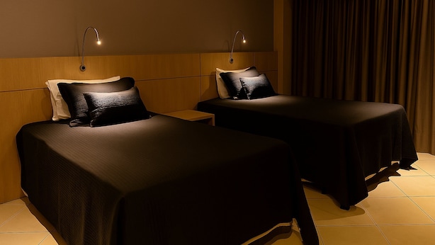 A hotel room with two single beds, each with a pillow and a nightstand. - Flat Próximo ao Riocentro - Barra da Tijuca (Rio de Janeiro)