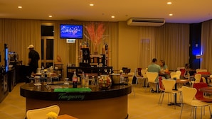 A hotel lobby with a reception desk, a bar area, and several dining tables and chairs. - Flat Próximo ao Riocentro - Barra da Tijuca (Rio de Janeiro)