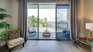 Uma varanda com vista para uma piscina e árvores, uma cadeira, uma mesa e um abajur.