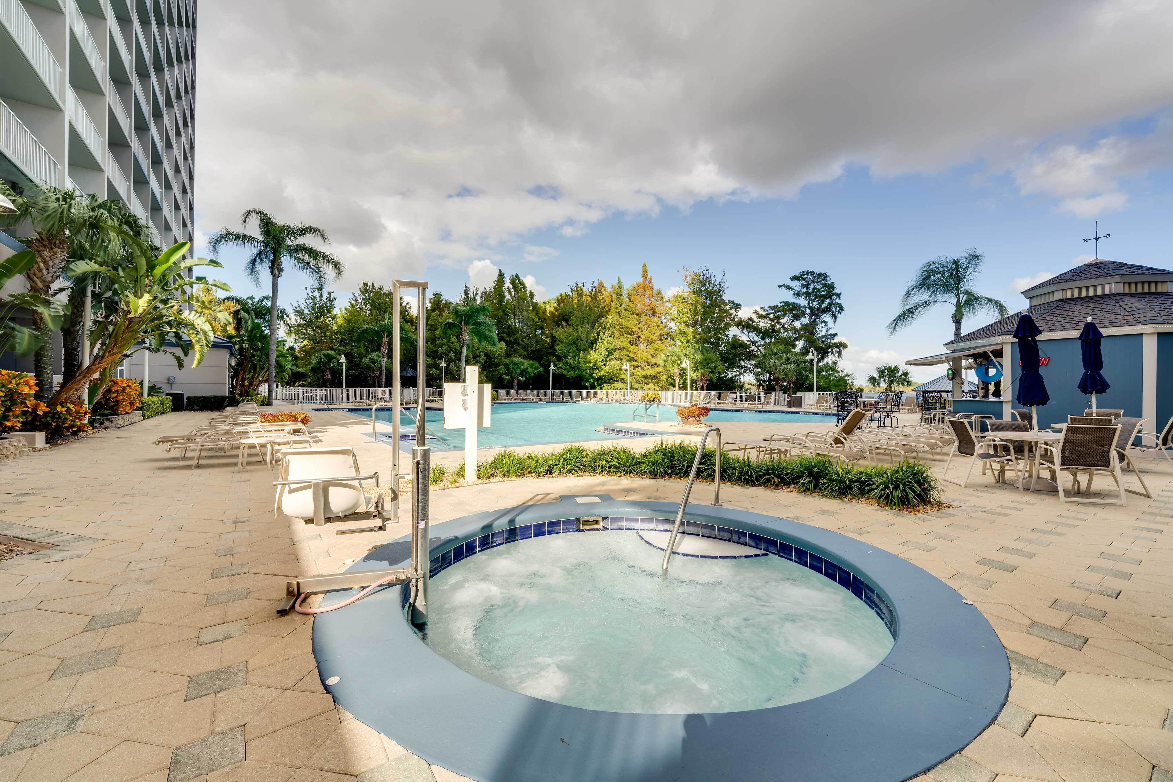 A hotel pool area with a hot tub, lounge chairs, and a view of the pool.
