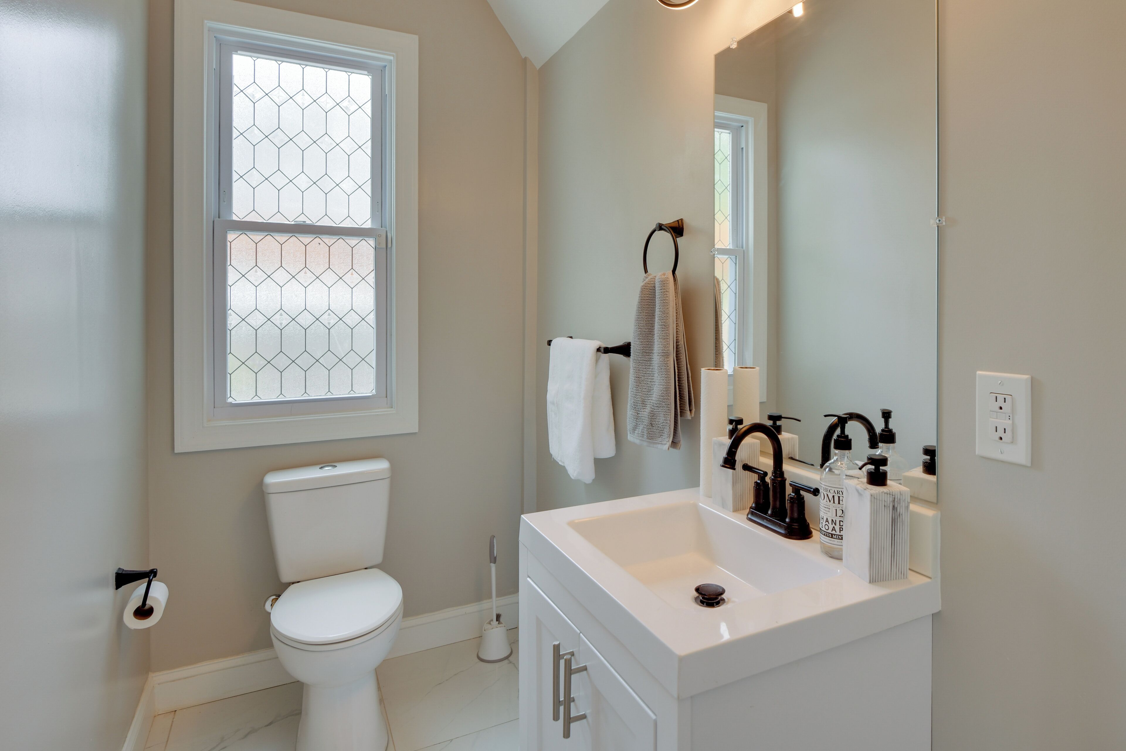 A modern bathroom with a toilet, sink, and large mirror.
