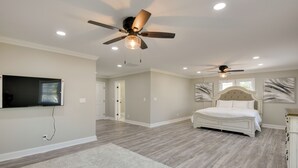 A spacious bedroom with a large bed, two ceiling fans, a TV mounted on the wall, and a walk-in closet. - 5 Mi to Inner Harbor: Expansive Family Getaway (Baltimore)
