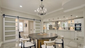 A modern kitchen with white cabinets, a central island, and a chandelier. - 5 Mi to Inner Harbor: Expansive Family Getaway (Baltimore)