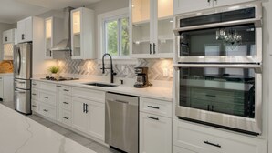 A modern kitchen with white cabinetry, stainless steel appliances, and a built-in oven. - 5 Mi to Inner Harbor: Expansive Family Getaway (Baltimore)