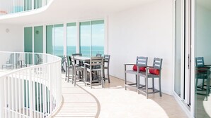 A modern balcony with a dining area, a white railing, and a view of the sea. - DOWN BY THE BAY! 4 Bedroom Gulf Facing unit! ASK ABOUT DISCOUNTS!  (Orange Beach)