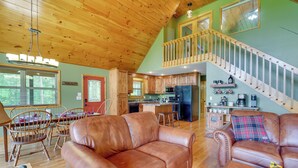 A spacious living room with leather sofas, wooden flooring, and a staircase leading to an upper level. - Murphy Cabin w/ Hot Tub, Fire Pit & Mountain Views (Murphy)
