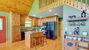 A kitchen with wooden cabinets, a black refrigerator, and a wooden island with stools. - Murphy Cabin w/ Hot Tub, Fire Pit & Mountain Views (Murphy)