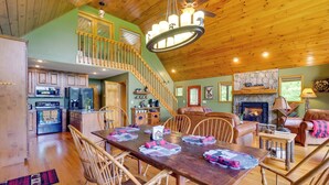 A spacious living area with a wooden ceiling, a dining table with placemats, and a fireplace. - Murphy Cabin w/ Hot Tub, Fire Pit & Mountain Views (Murphy)