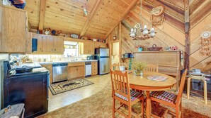 Una cocina rústica con armarios de madera, una estufa y un comedor con mesa y sillas.