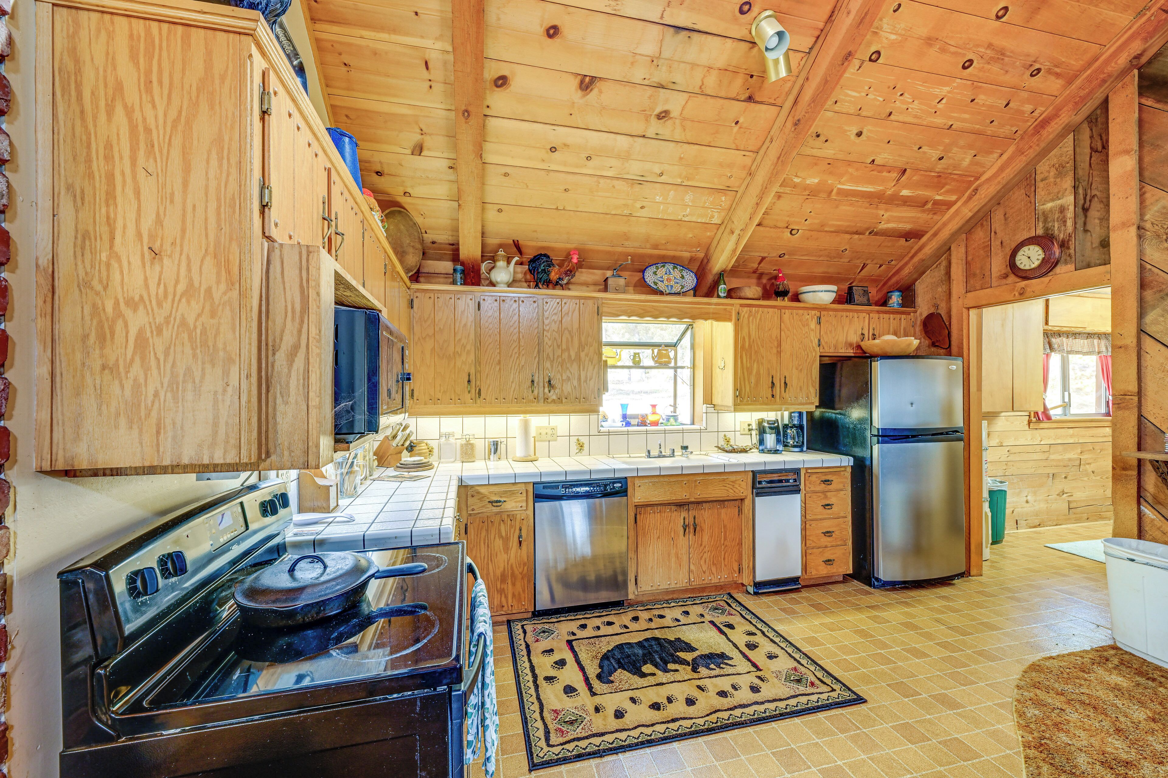 A wooden cabin kitchen with a stove, refrigerator, and wooden cabinets.