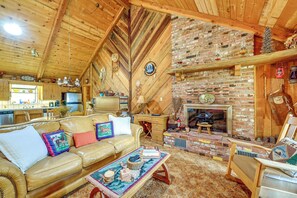 A cozy cabin interior with a wooden ceiling, a brick fireplace, a leather sofa, and a dining area. - Countryside Views: Family-friendly Badger Cabin (Badger)