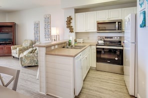 A compact kitchen with white cabinets, a built-in microwave, and an oven.