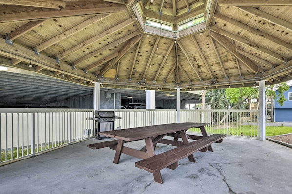 A covered picnic area with a wooden bench and grill.