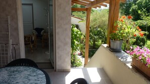 Una zona patio riparata con tavolo e sedie, un gazebo in legno e piante in vaso.
