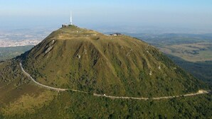 Vista aerea di una montagna con una strada che si snoda lungo il suo fianco e una torre bianca sulla cima.