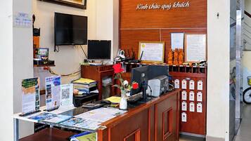 A reception desk with a wooden counter, a scale, and a clock on the wall.