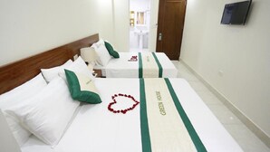 Une chambre d’hôtel avec deux lits, chacun agrémenté d’un couvre-lit à rayures vertes et d’une décoration en forme de cœur posée sur le lit.