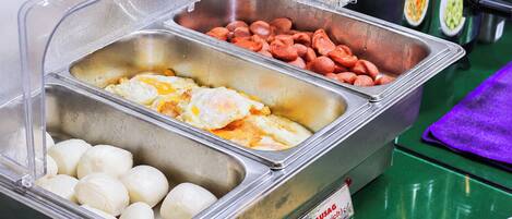 A buffet with labeled food sections including fried eggs, sausages, and dumplings.