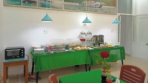 Un espace repas avec un buffet, un four à micro-ondes et une table agrémentée d’un arrangement floral de roses.